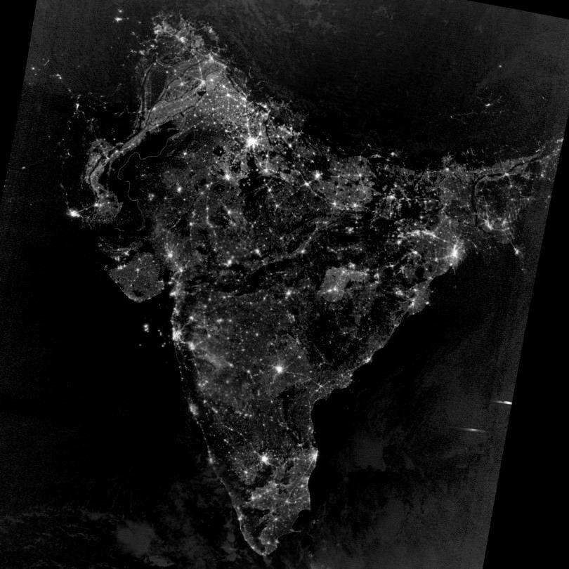 A satellite photograph of India at night in 2012. We see that major metros are clearly visible and that large parts of the country are electrified.
